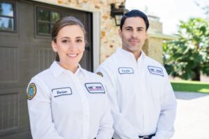 Two AC Repair techs from One Hour outside a home smiling at camera