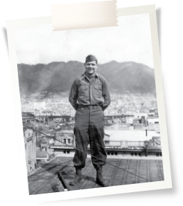 old photo of a veteran standing in front of a battlefield.